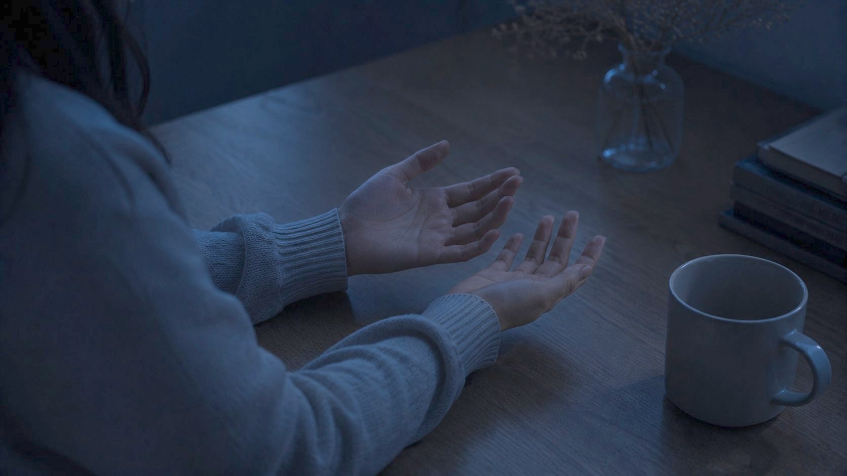 夜、机の上で開かれた両の手のひら