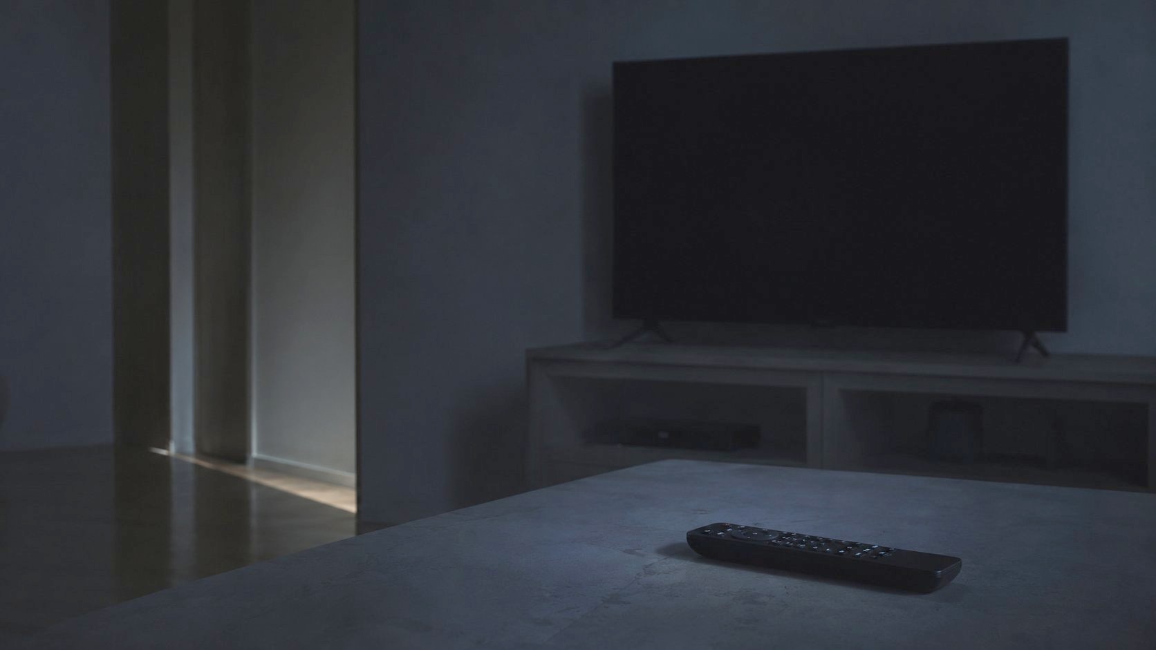 テレビの消えた暗いリビングとリモコン