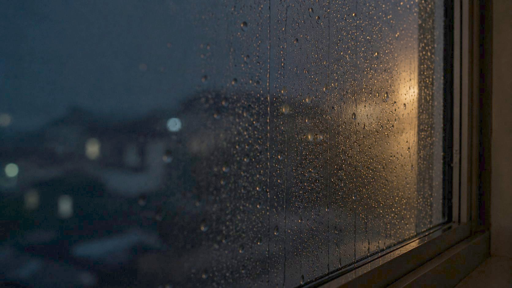 夜の雨に濡れた窓ガラスを伝う雫